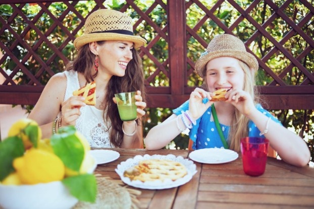 A mother and daughter enjoying an apple pie outside.